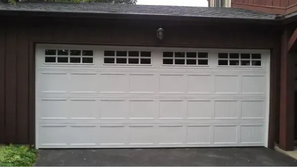 White garage door with rectangular window panes. Brown exterior walls.