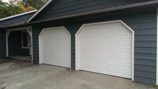 Two white garage doors on a dark blue house.