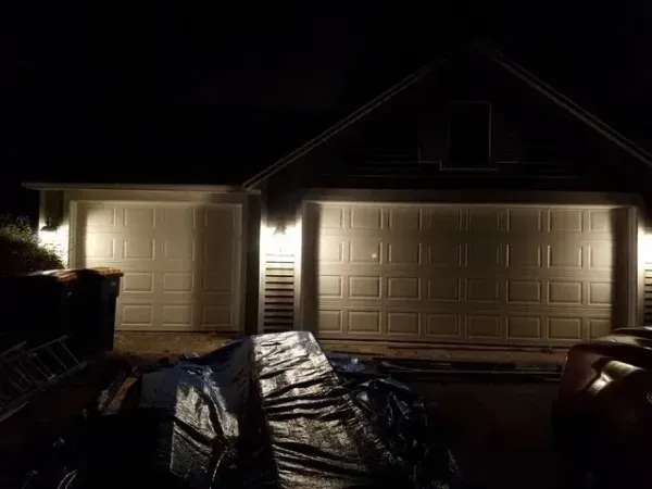 Garage doors lit at night, with debris in the foreground.