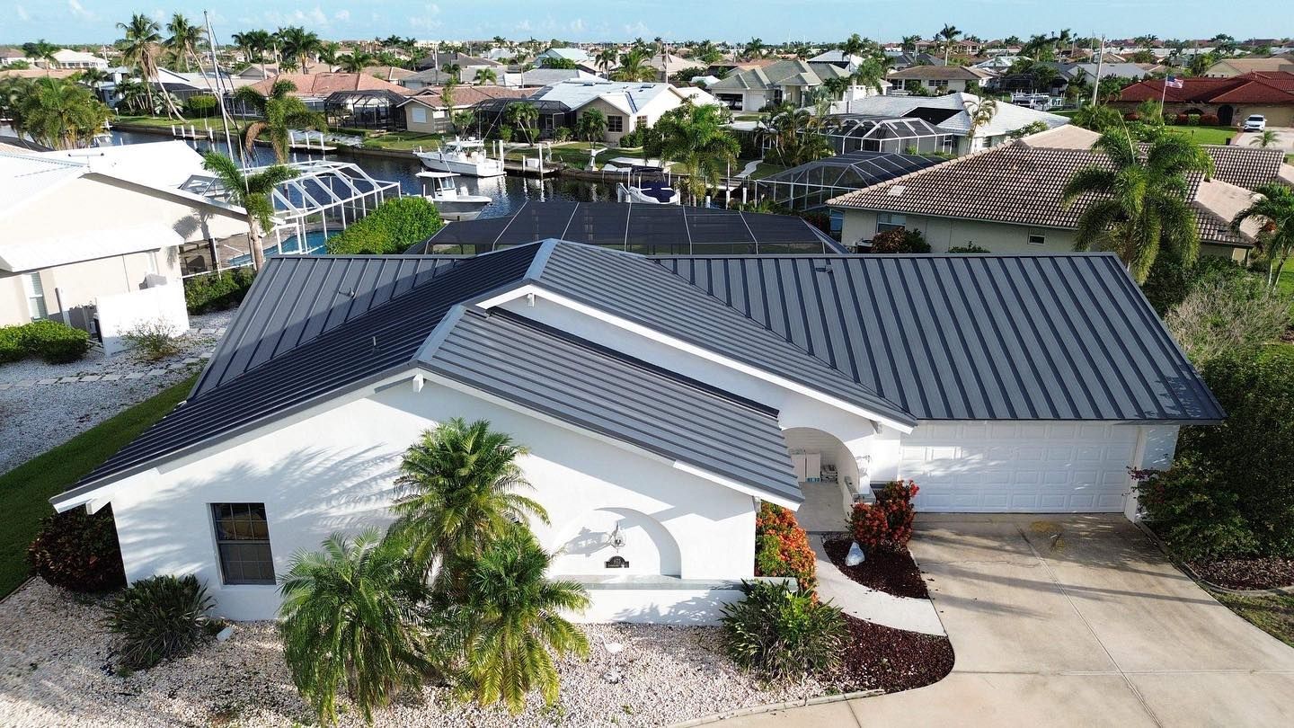An aerial view of a white house with a black roof