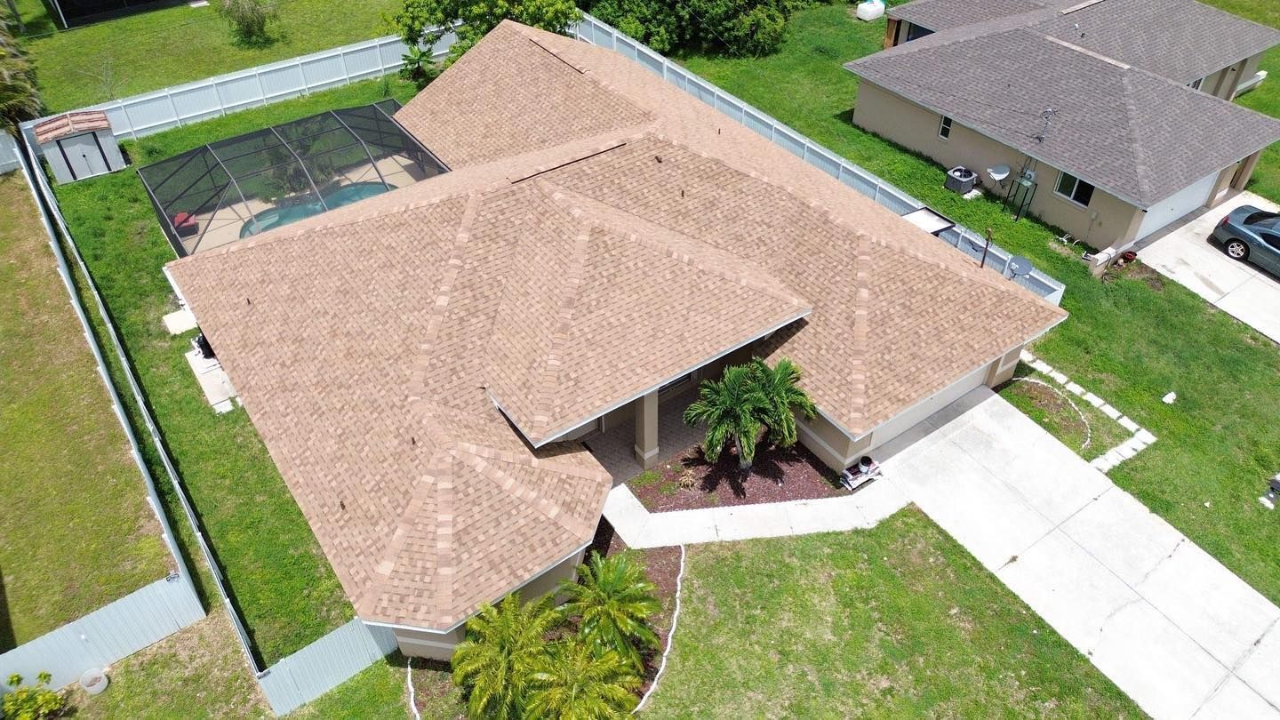An aerial view of a house with a brown roof and a pool.