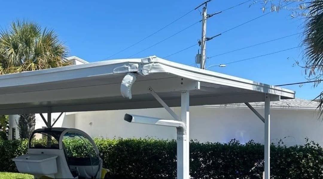 A golf cart is parked under a carport in front of a house.