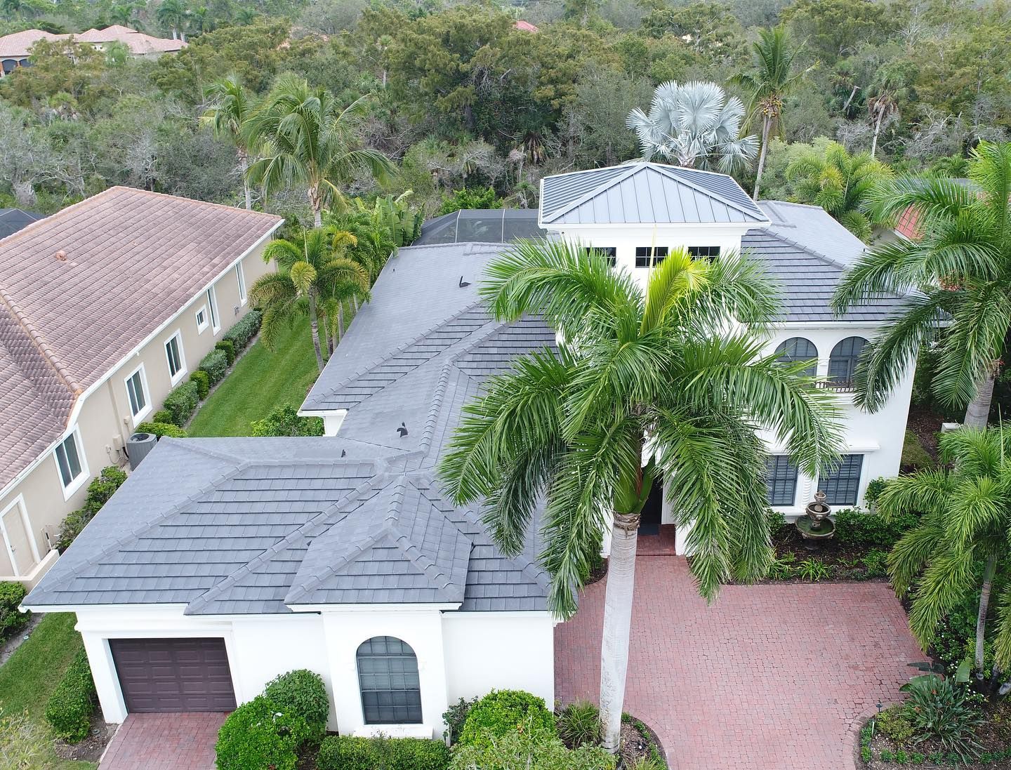 An aerial view of a large house with a palm tree in front of it.