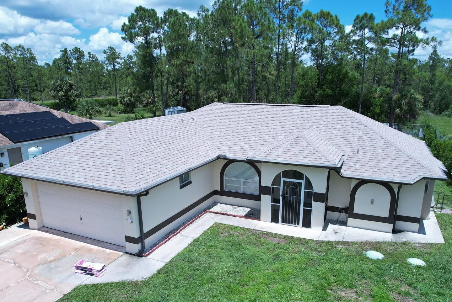 An aerial view of a house with a gray roof surrounded by trees.