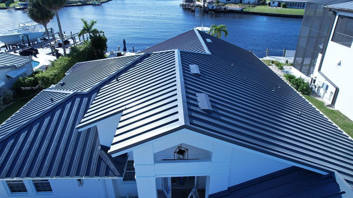 An aerial view of a house with a blue roof and a river in the background.