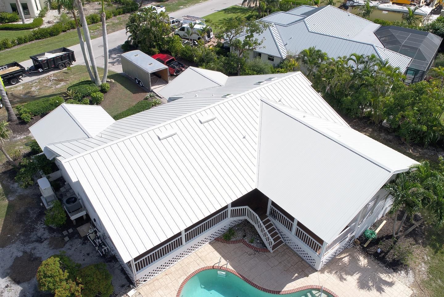 An aerial view of a house with a pool and a white roof