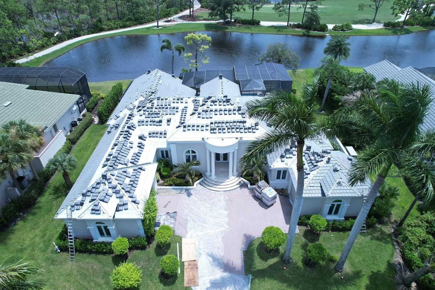 An aerial view of a large white house surrounded by palm trees