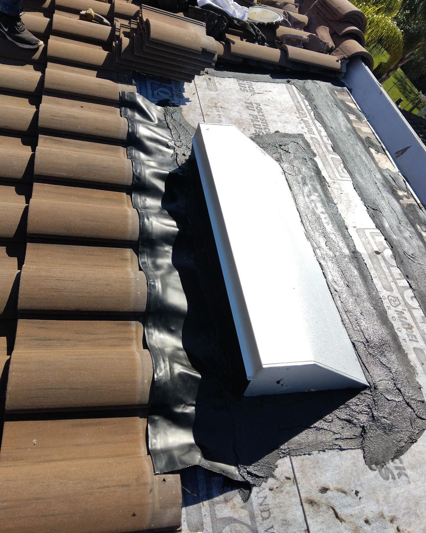 A roof with brown tiles and a white box on it