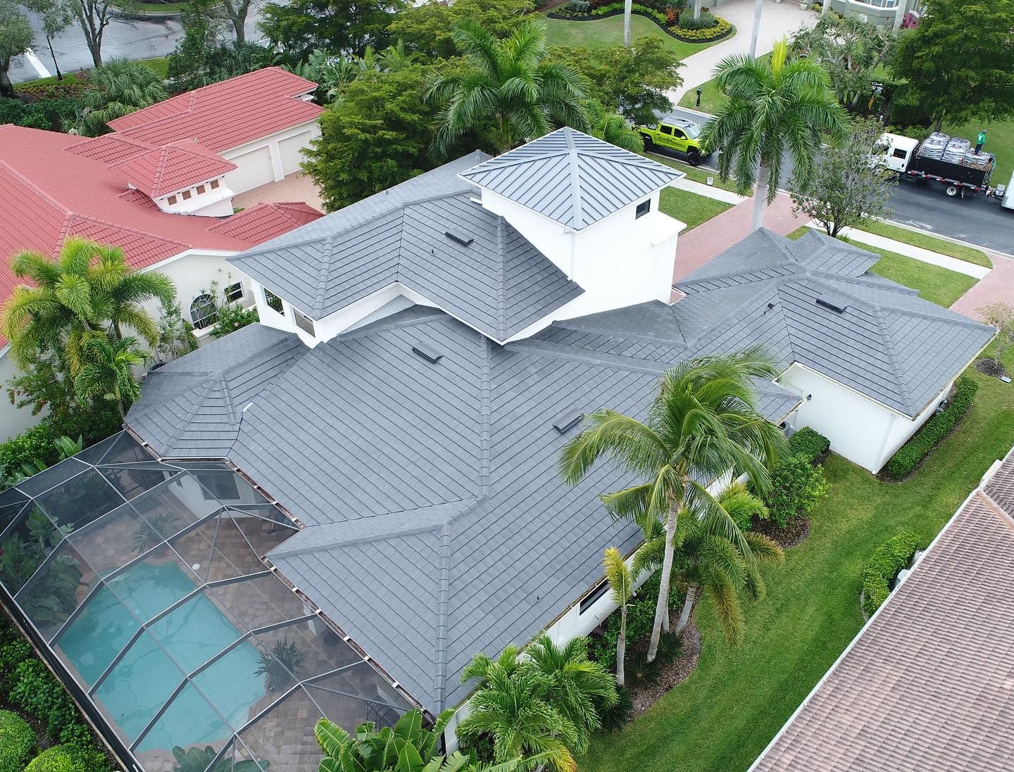 An aerial view of a house with a gray roof and a pool.