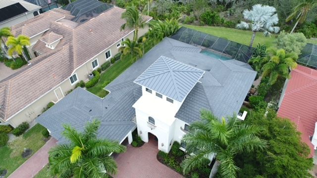An aerial view of a large house with a tennis court in the background.