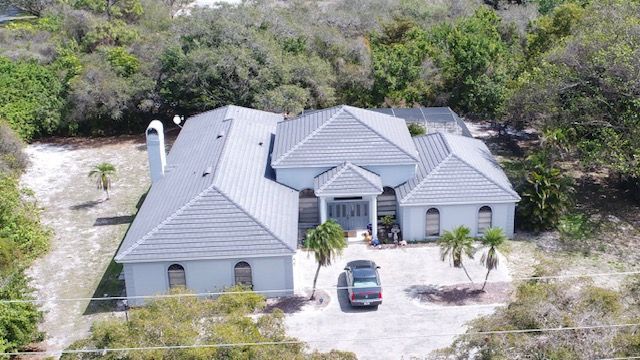 An aerial view of a large white house with a car parked in front of it.
