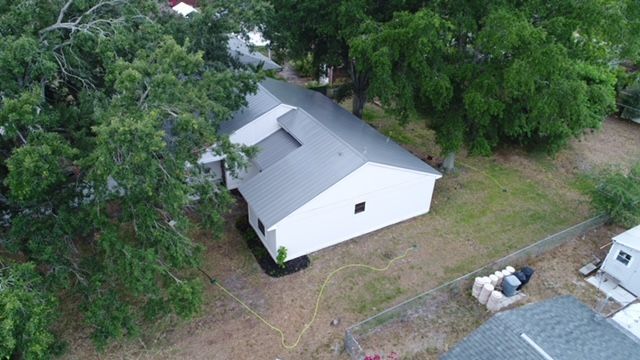 An aerial view of a white house surrounded by trees.