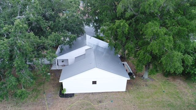 An aerial view of a white house surrounded by trees.