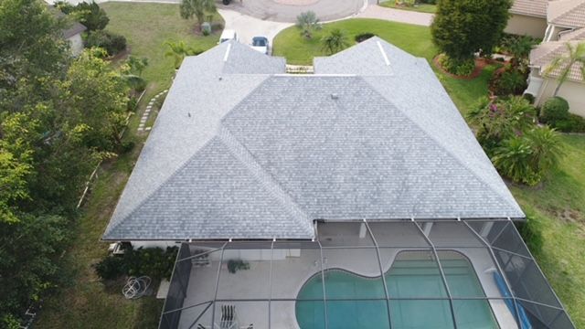 An aerial view of a house with a pool and a roof.