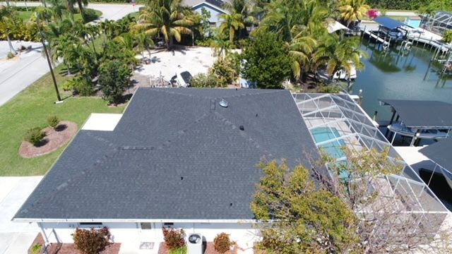 An aerial view of a house with a black roof and a pool.