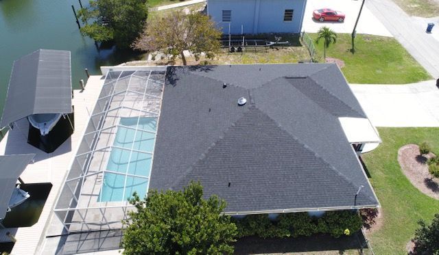 An aerial view of a house with a pool and a boat in the background.