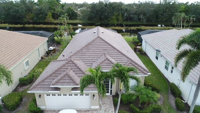 An aerial view of a house with a tile roof in a residential area.