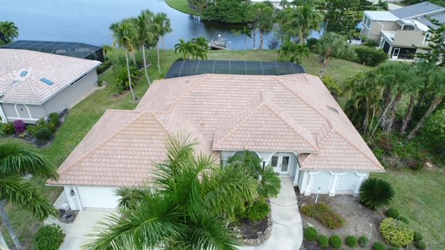 An aerial view of a house with a tile roof surrounded by palm trees.