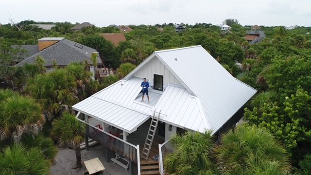 An aerial view of a man standing on the roof of a house.