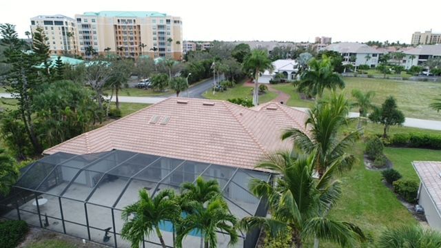 An aerial view of a house with a screened in pool and palm trees.