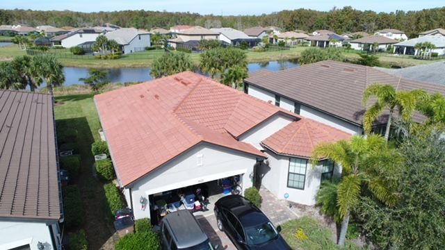 An aerial view of a house with a red roof and a black truck parked in front of it.