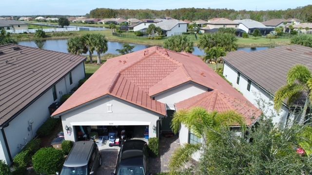 An aerial view of a house with a red tile roof and two cars parked in front of it.