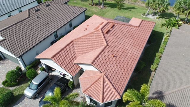 An aerial view of a house with a red roof and a car parked in front of it.