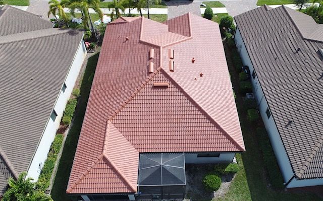 An aerial view of a house with a tiled roof surrounded by other houses.