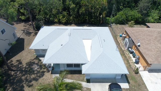 An aerial view of a house with a white roof and a car parked in front of it.