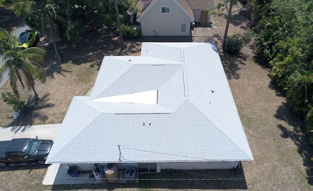An aerial view of a house with a white roof and a black truck parked in front of it.