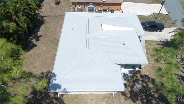 An aerial view of a house with a white roof and a car parked in front of it.