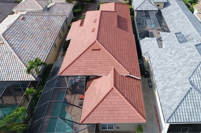 An aerial view of a house with a red tile roof surrounded by other houses.