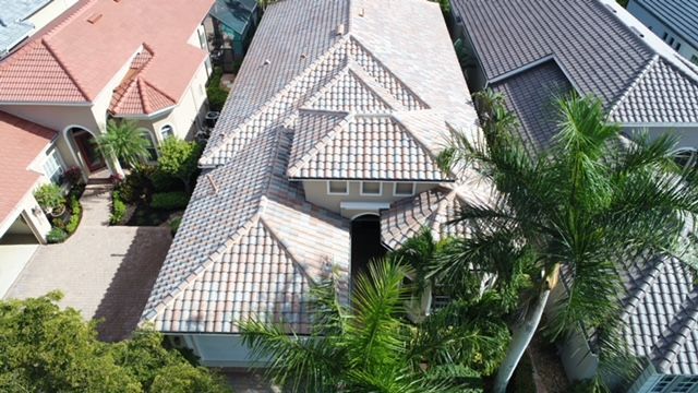 An aerial view of a house with a tiled roof surrounded by palm trees.