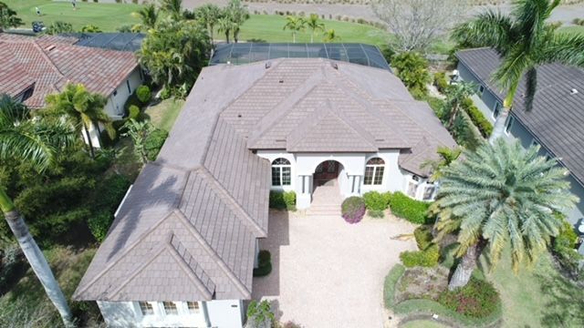 An aerial view of a large house with a large driveway surrounded by palm trees.