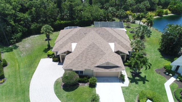 An aerial view of a house with a large driveway surrounded by trees.