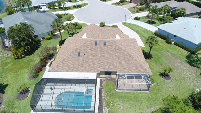 An aerial view of a house with a pool in a residential area.