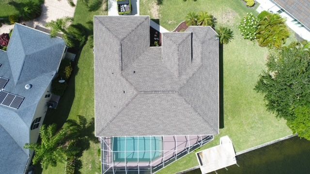 An aerial view of a house with a roof and a pool.