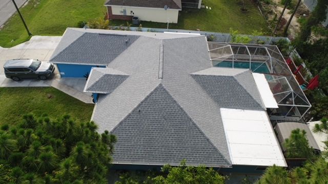 An aerial view of a house with a roof and a pool.