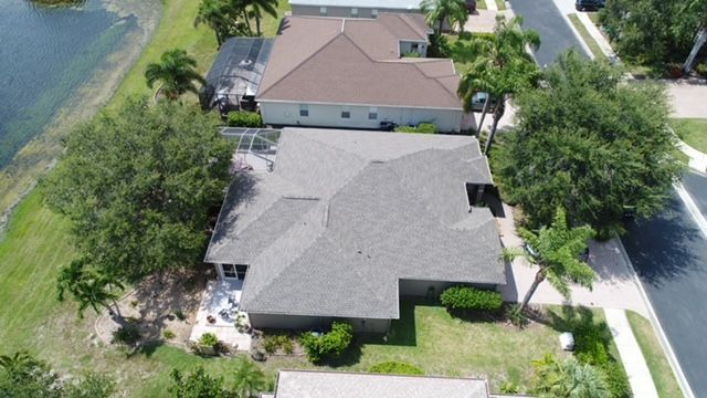 An aerial view of a house in a residential area with a lake in the background.