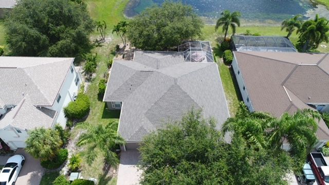 An aerial view of a house in a residential area with a lake in the background.