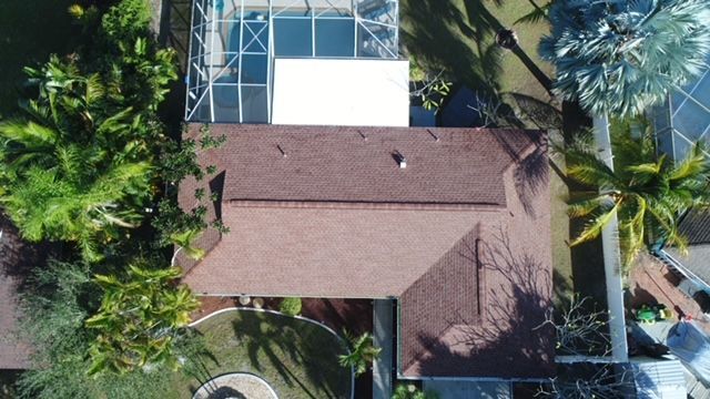 An aerial view of a house with a pool and palm trees.