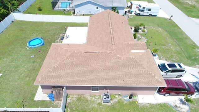 An aerial view of a house with a pool and cars parked in front of it.