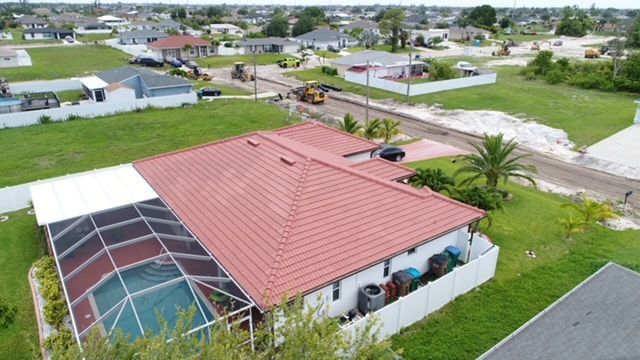 An aerial view of a house with a red roof and a pool