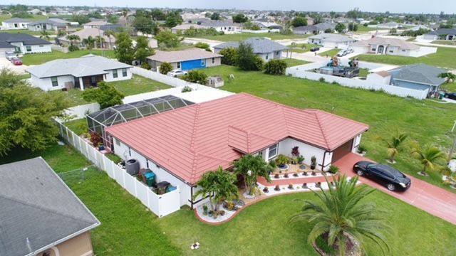 An aerial view of a house with a red roof in a residential area.
