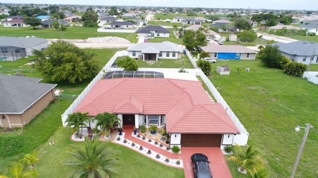 An aerial view of a house with a red roof and a car parked in front of it.