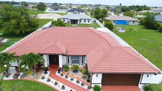 An aerial view of a house with a red tile roof in a residential area.