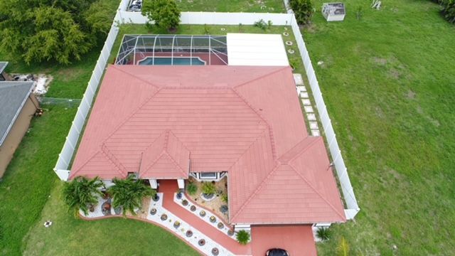 An aerial view of a house with a red tile roof and a pool.