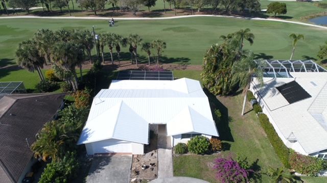 An aerial view of a house with a solar panel on the roof