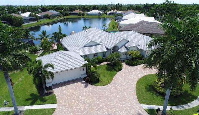 An aerial view of a house with a large driveway and a lake in the background.