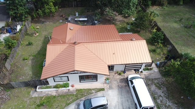 An aerial view of a house with a red roof and a white van parked in front of it.